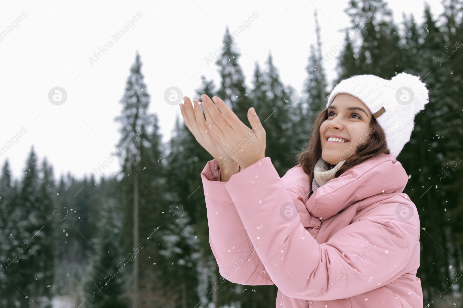 Photo of Happy young woman in warm clothes outdoors, space for text. Winter vacation