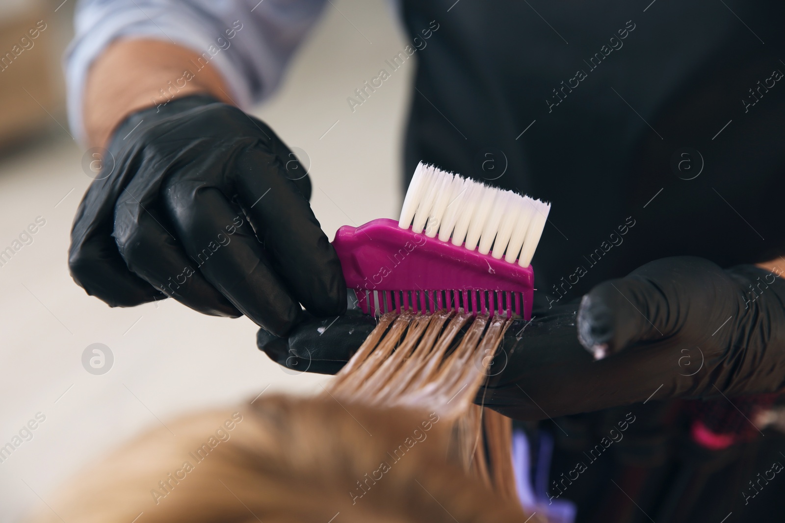 Photo of Professional hairdresser dying hair in beauty salon, closeup