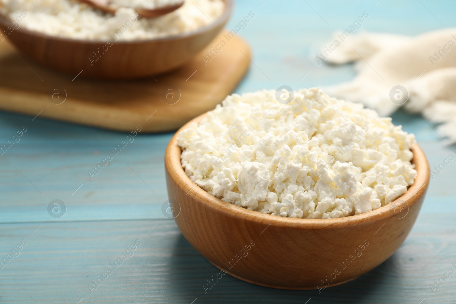 Photo of Delicious fresh cottage cheese on blue wooden table, closeup. Space for text