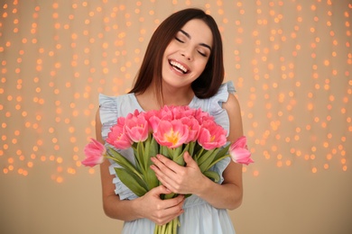 Photo of Portrait of smiling young girl with beautiful tulips on blurred background. International Women's Day