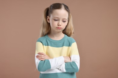 Photo of Portrait of sad girl with crossed arms on light brown background