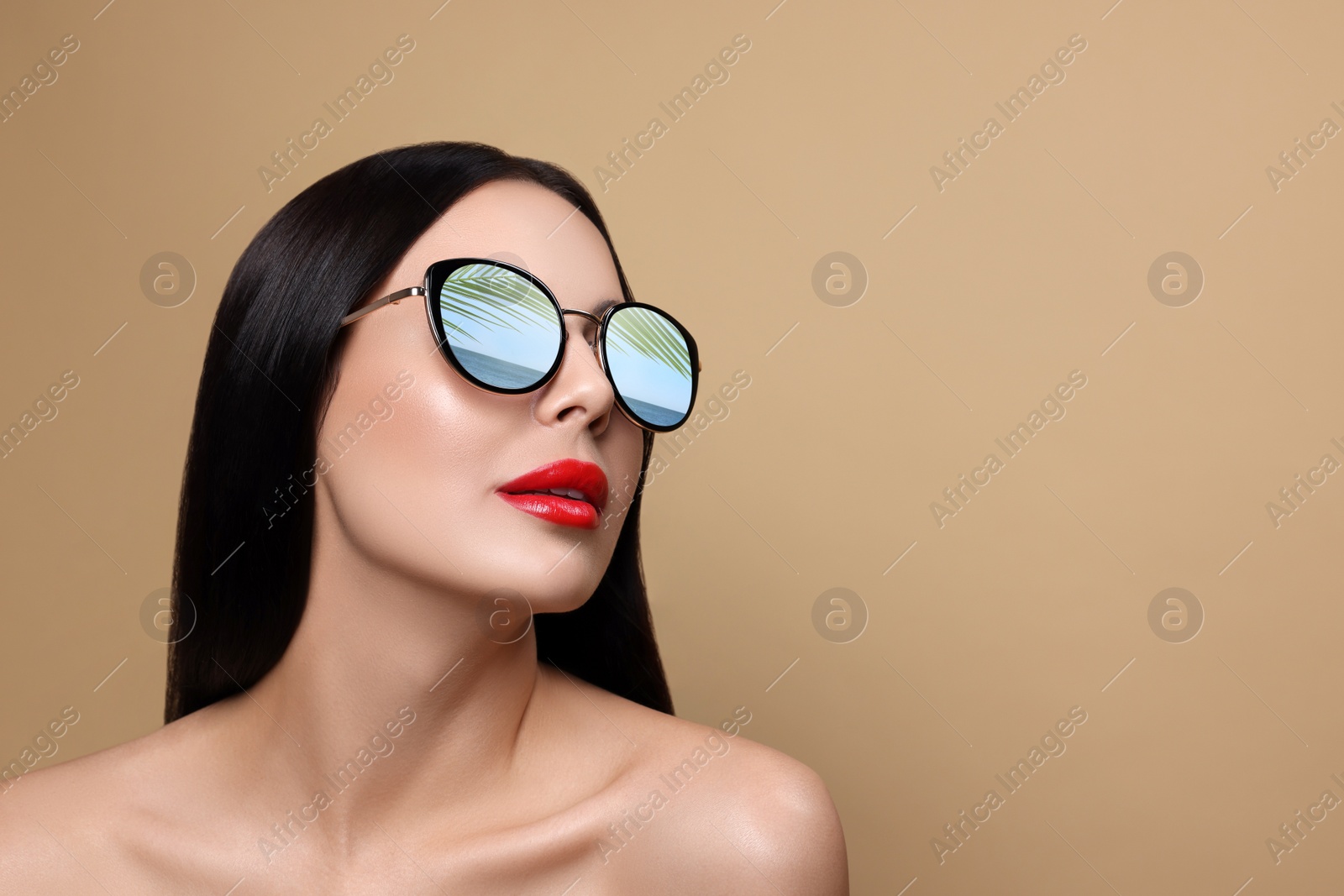 Image of Attractive woman in stylish sunglasses on dark beige background. Sea and palm leaf reflecting in lenses. Space for text