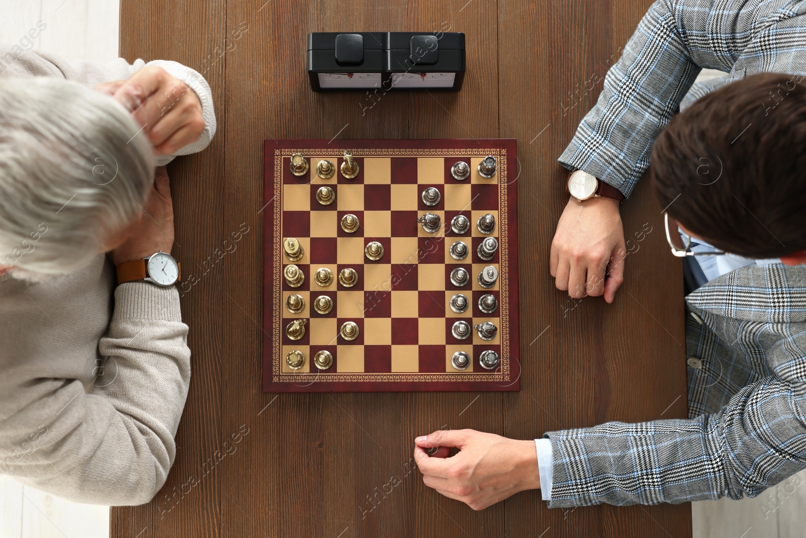 Photo of Men playing chess during tournament at wooden table, top view