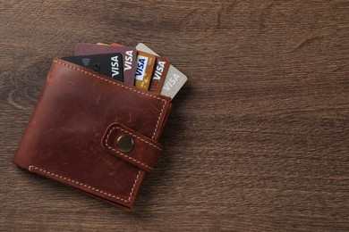 Photo of MYKOLAIV, UKRAINE - FEBRUARY 22, 2022: Wallet with Visa credit cards on wooden table, top view. Space for text