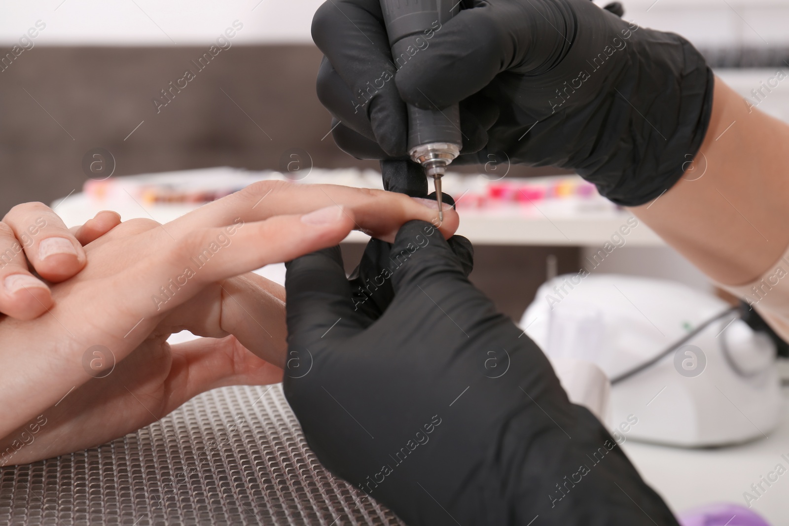 Photo of Professional manicurist working with client in salon, closeup