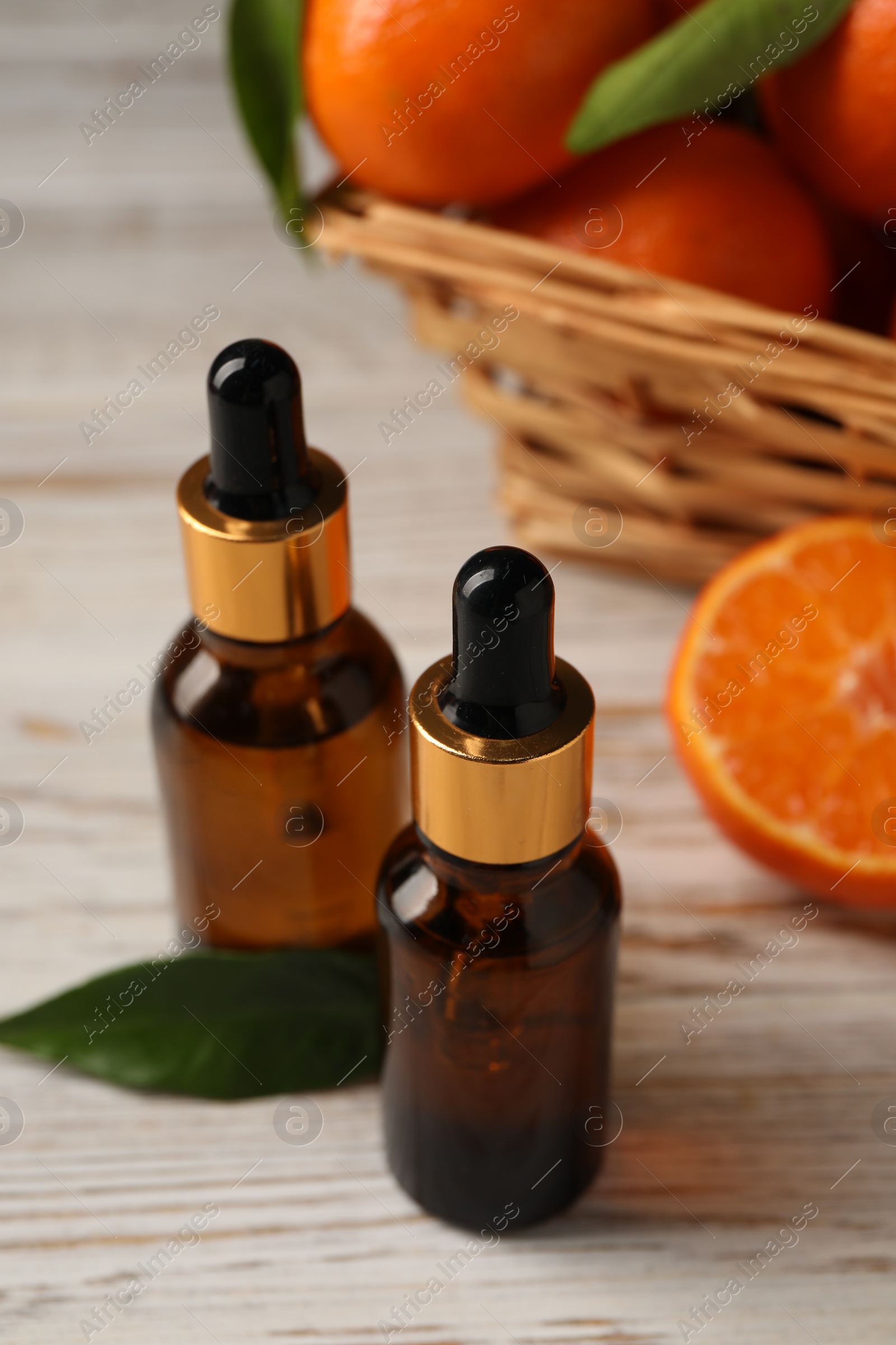 Photo of Bottles of tangerine essential oil on white wooden table