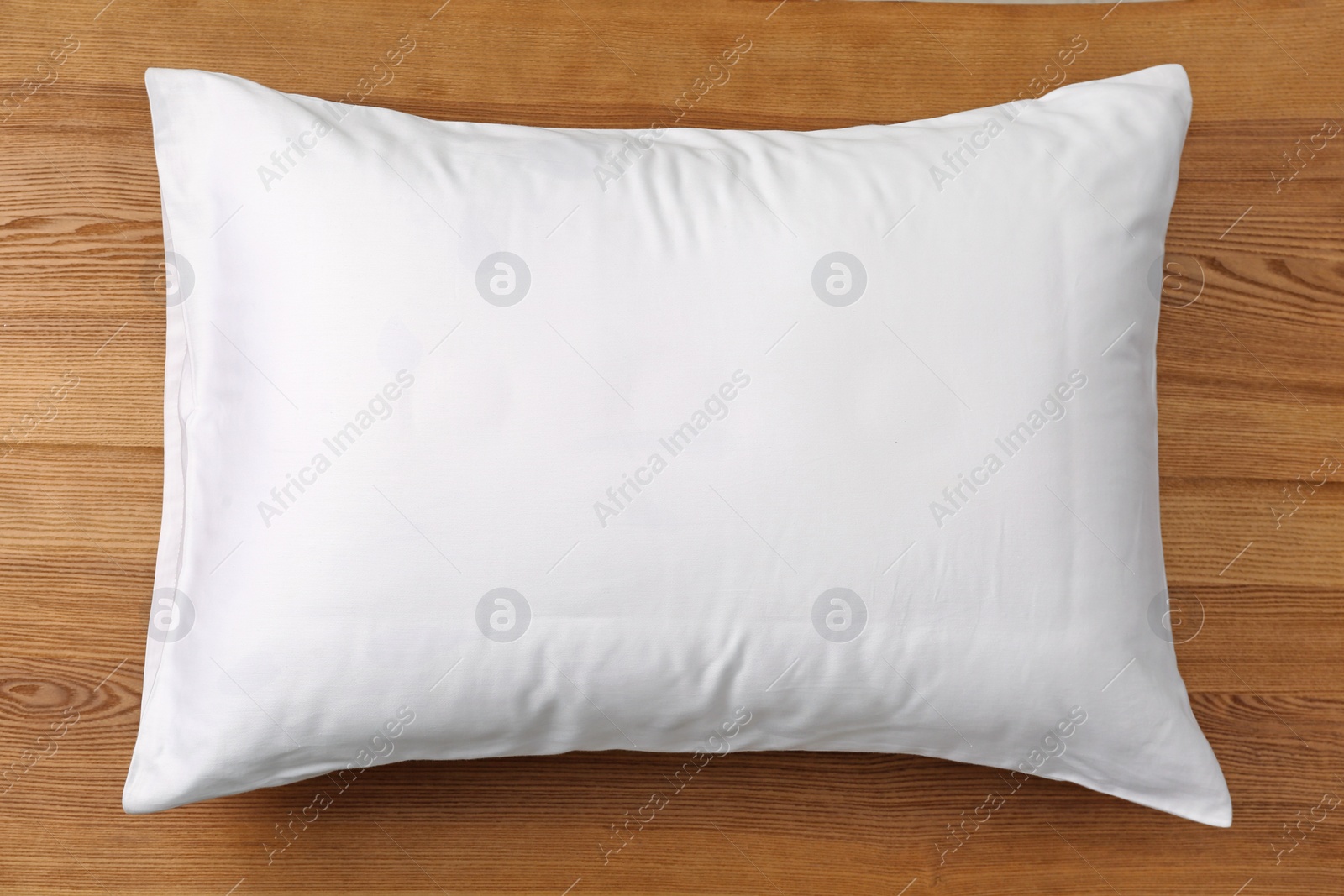 Photo of Soft bed pillow on wooden background, top view