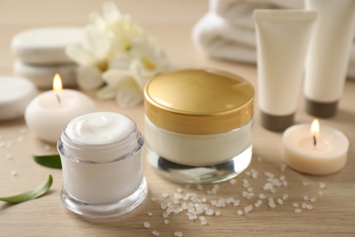 Photo of Composition with skin care products and candles on wooden table, closeup