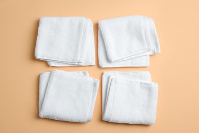 Photo of White soft folded towels on pale orange background, flat lay