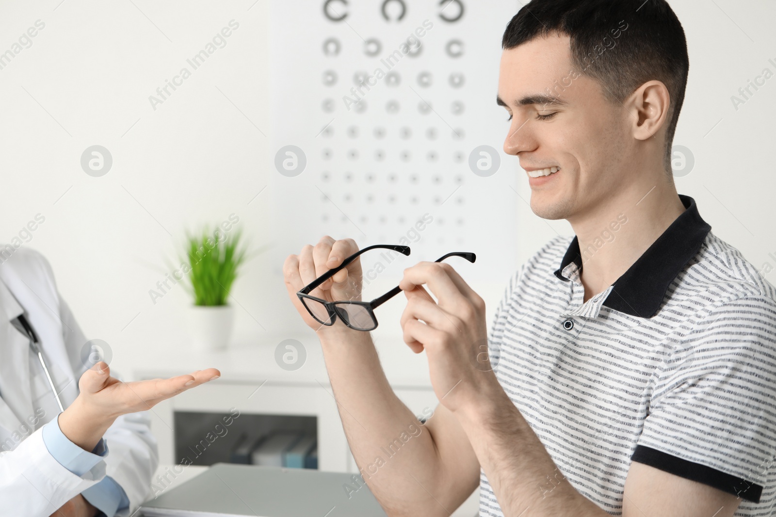 Photo of Vision testing. Young man trying glasses at ophthalmologist office