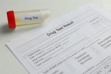Photo of Drug test result form and container with urine sample on light table, closeup