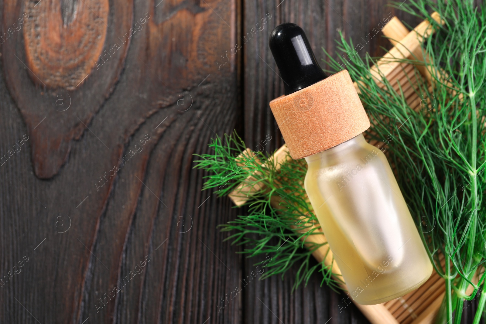 Photo of Bottle of essential oil and fresh dill on wooden table, flat lay. Space for text