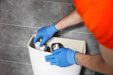Plumber repairing toilet bowl in water closet, closeup