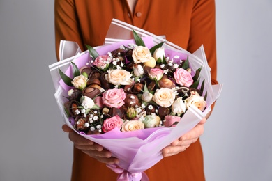 Photo of Woman with beautiful food bouquet on light grey background, closeup