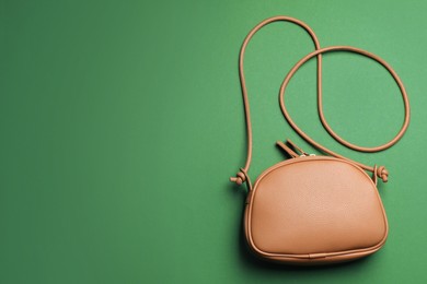 Stylish woman's bag on green background, top view. Space for text