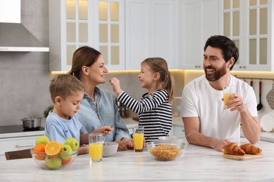 Photo of Happy family having breakfast at table in kitchen