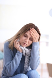 Woman with headache suffering from cold on blurred background