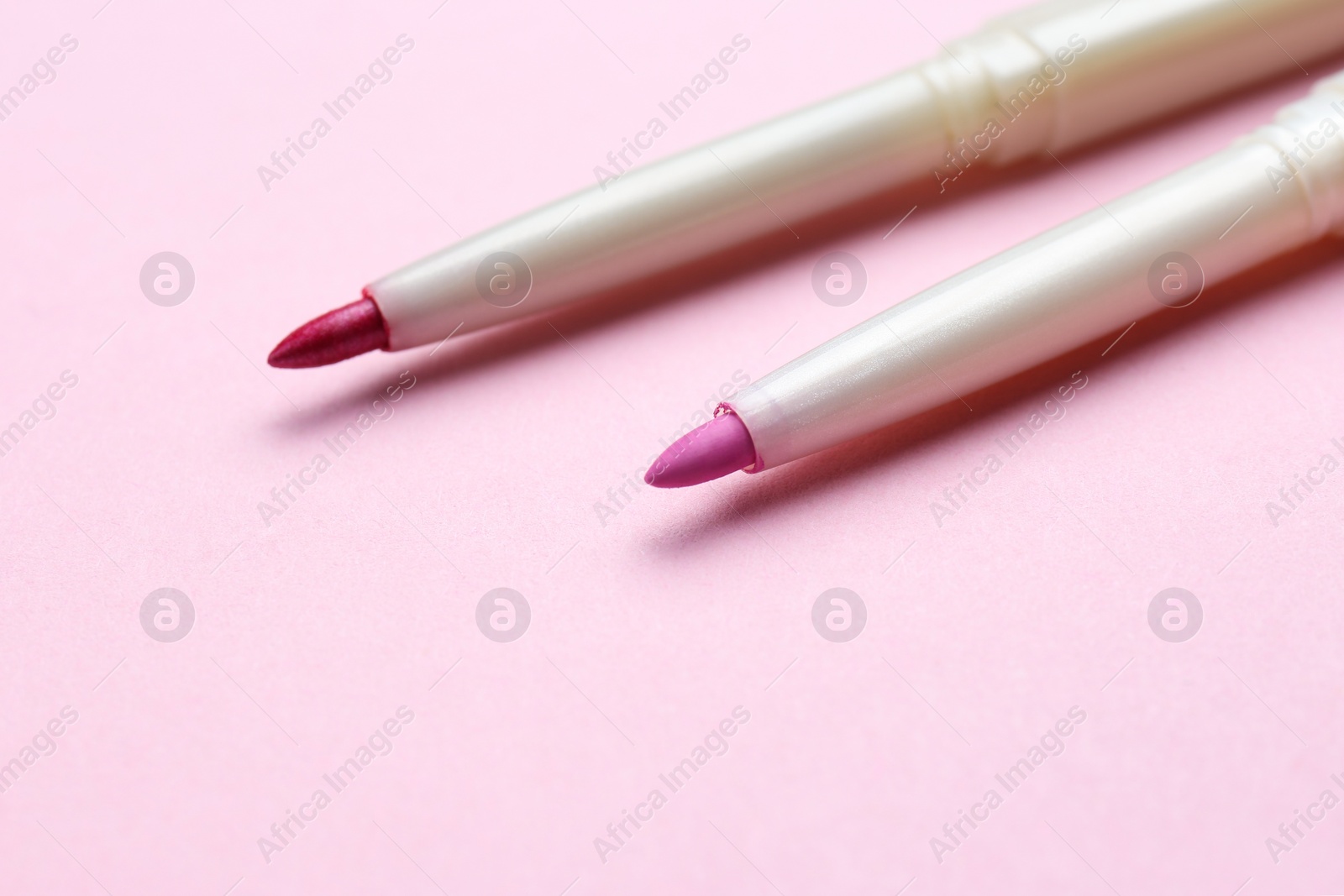 Photo of Lip pencils on pink background, closeup. Cosmetic product