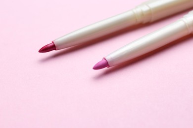 Lip pencils on pink background, closeup. Cosmetic product