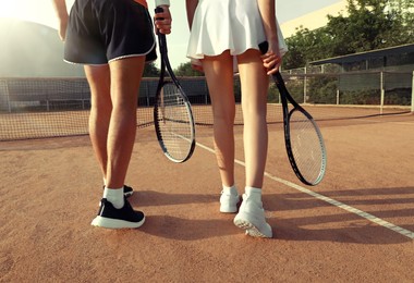 Photo of Couple with tennis rackets at court on sunny day, closeup