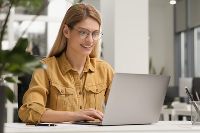 Woman working on laptop at white desk in office