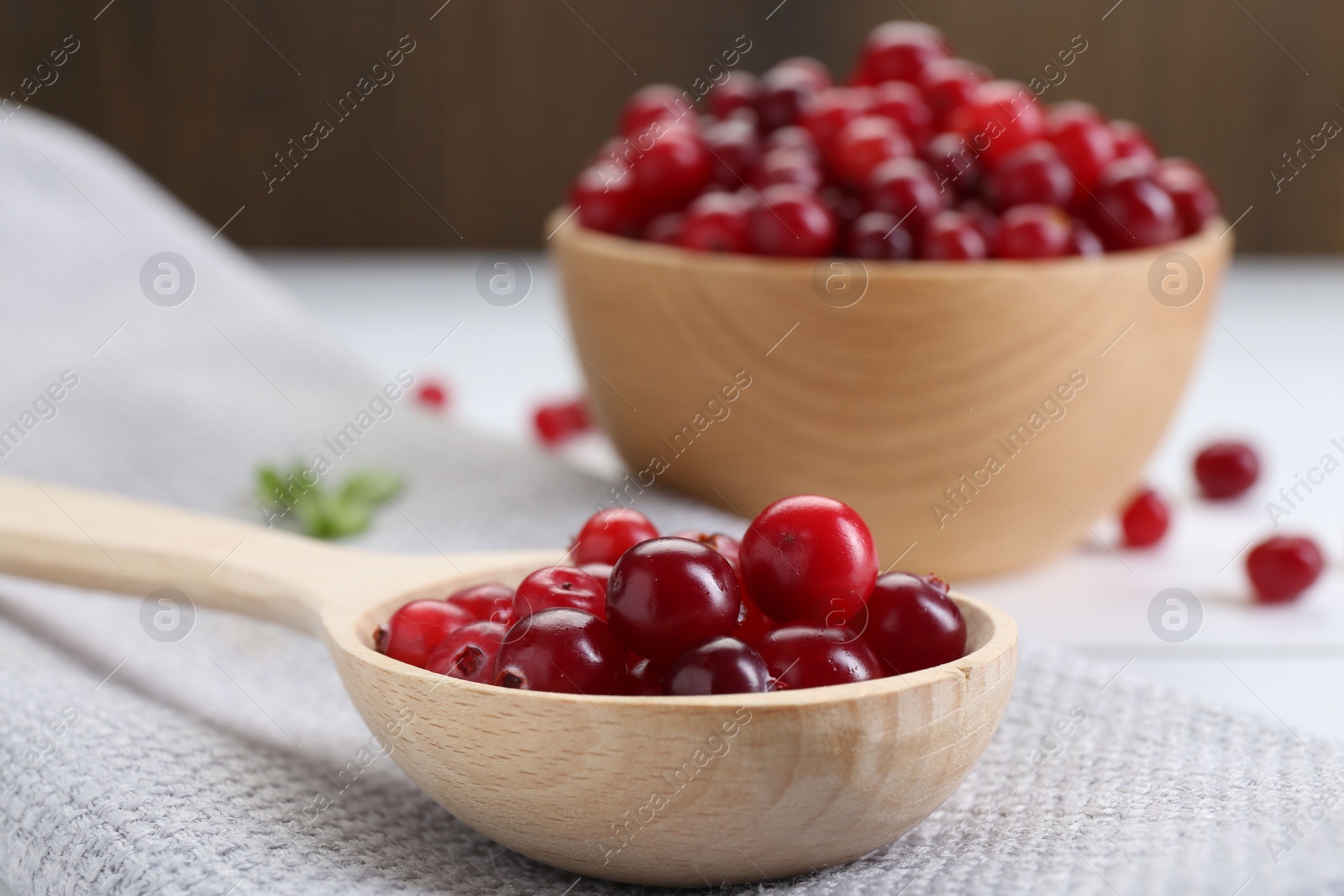 Photo of Spoon with fresh ripe cranberries on table, closeup