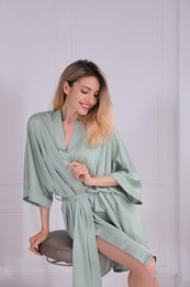 Photo of Pretty young woman in beautiful silk robe sitting on stool at home
