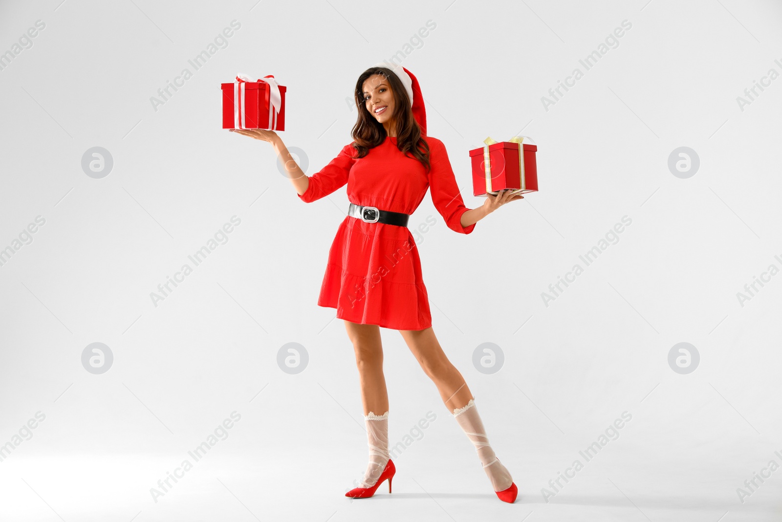Photo of Beautiful woman wearing Christmas costume with gifts on white background