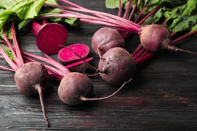 Cut and whole raw beets on wooden table