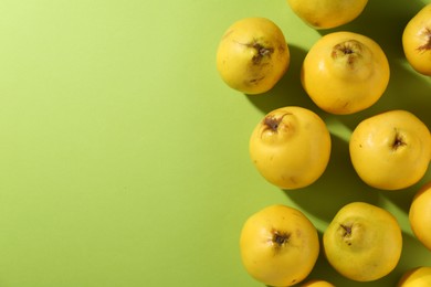 Tasty ripe quinces on light green background, flat lay. Space for text