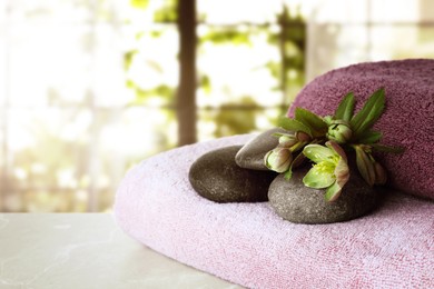 Image of Towels, spa stones and flowers on table in salon, space for text