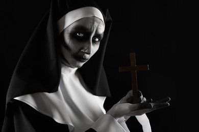 Scary devilish nun with cross on black background. Halloween party look