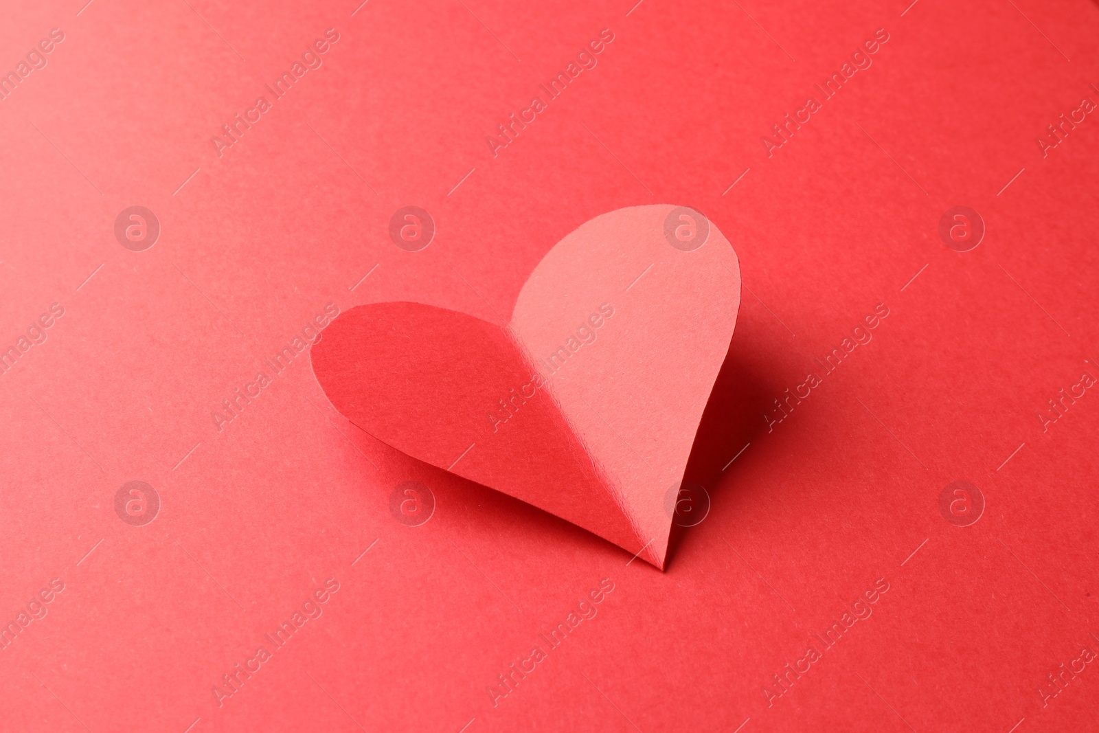 Photo of One bright paper heart on red background