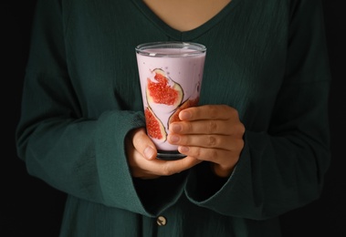 Photo of Woman holding fig smoothie on black background, closeup