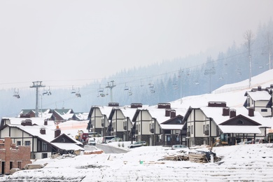 Photo of Beautiful view of ski resort with many cottages on snowy day. Winter vacation