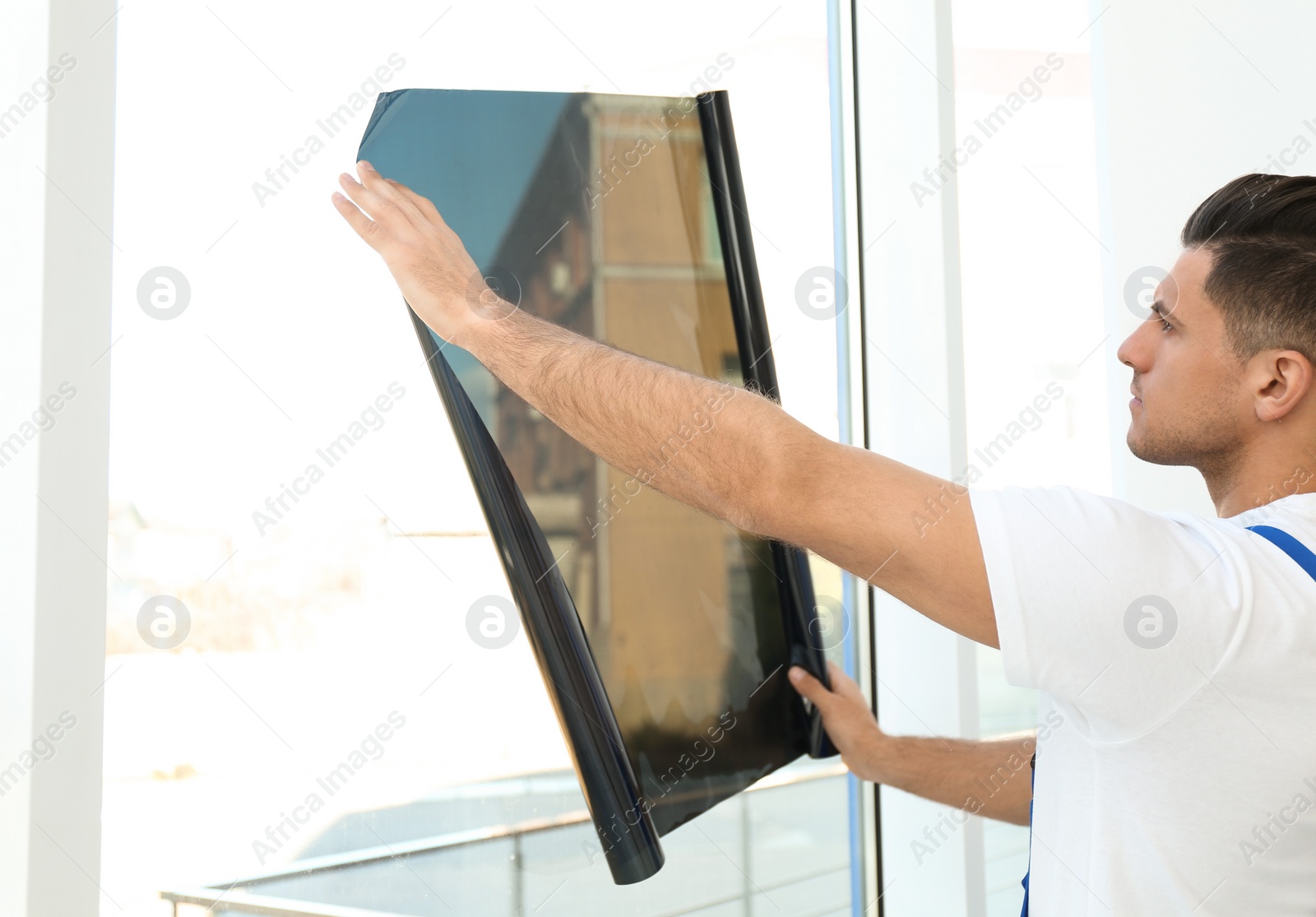 Photo of Professional worker tinting window with foil indoors