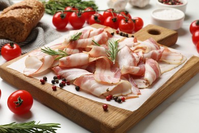 Photo of Slices of raw bacon and fresh products on white table, closeup