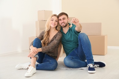 Photo of Happy young couple with key from their new house indoors