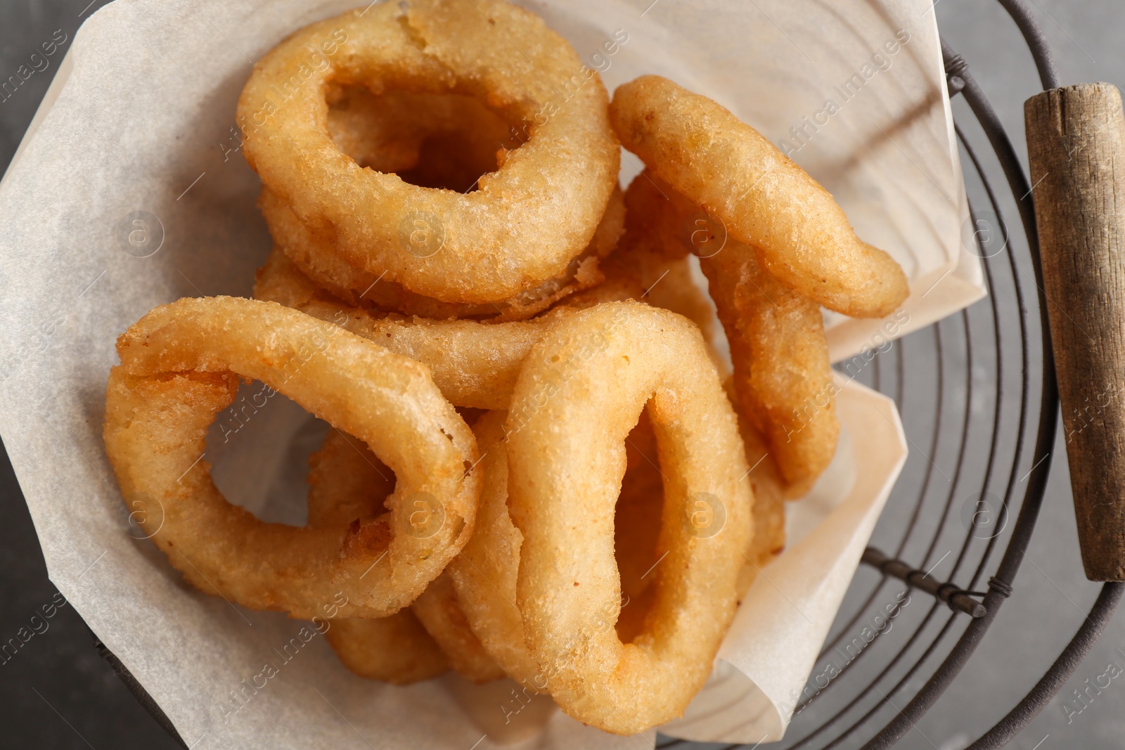 Photo of Basket with tasty crunchy onion rings, closeup