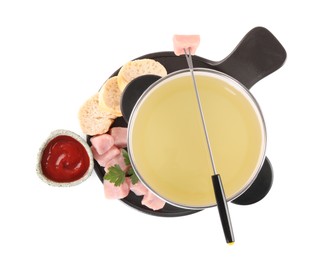 Photo of Fondue pot with oil, fork, raw meat pieces and other products isolated on white, top view