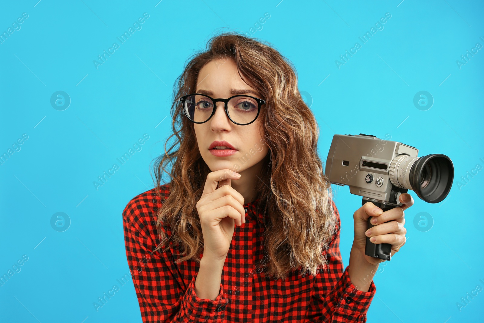 Photo of Beautiful young woman with vintage video camera on light blue background