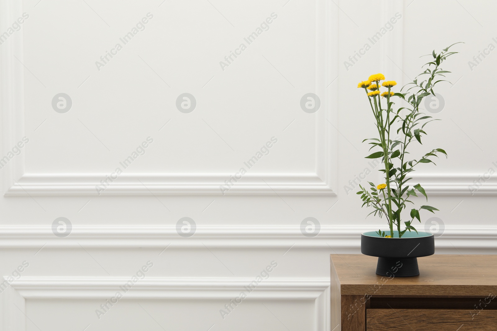 Photo of Ikebana art. Beautiful yellow flowers and green branch carrying cozy atmosphere at home, space for text