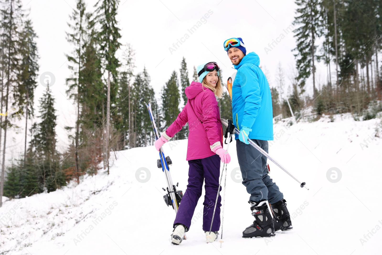 Photo of Couple of skiers on slope at resort. Winter vacation