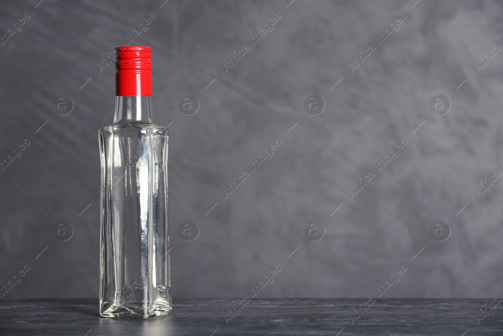 Photo of Glass bottle with vinegar on grey background. Space for text