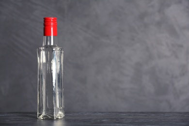 Photo of Glass bottle with vinegar on grey background. Space for text