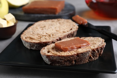Photo of Bread with delicious quince paste on black plate, closeup