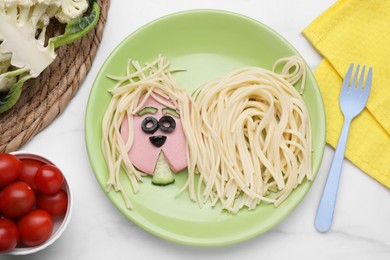 Photo of Creative serving for kids. Plate with cute dog made of tasty pasta, sausage and cucumber on white marble table, flat lay