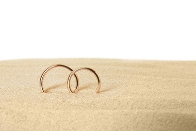 Honeymoon concept. Two golden rings and sand isolated on white