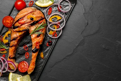 Photo of Tasty salmon steak served on black table, top view. Space for text