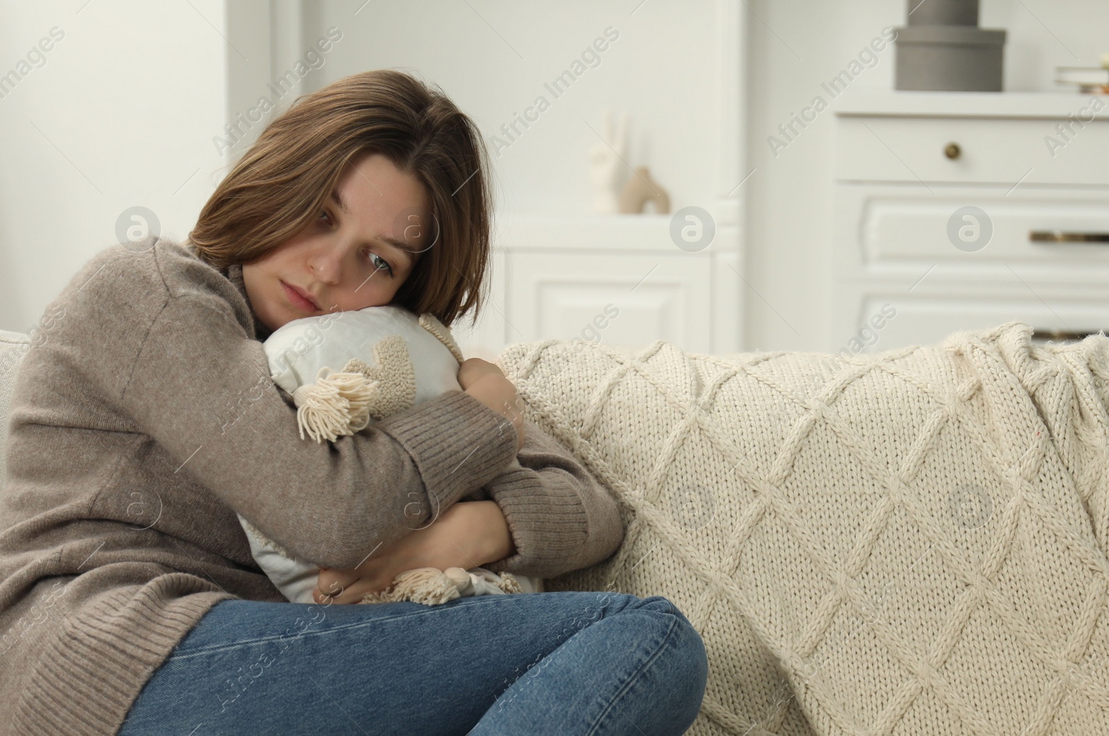 Photo of Sad young woman sitting on sofa at home, space for text